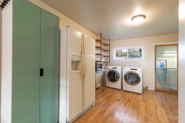 clothes washing area with light wood-style floors, laundry area, and washing machine and clothes dryer