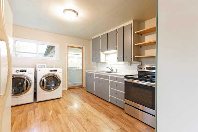 washroom with washing machine and clothes dryer, laundry area, a sink, and light wood-type flooring