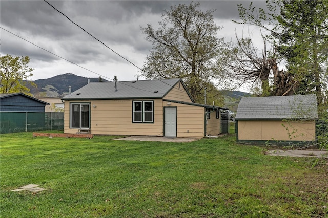 back of property with fence, a mountain view, a yard, and a patio area