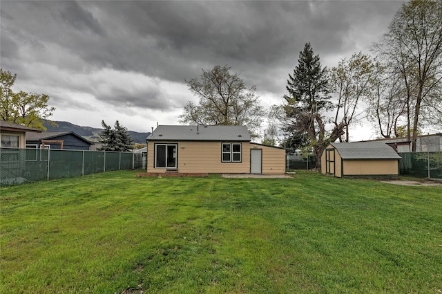 back of property with a lawn, an outdoor structure, a shed, and a fenced backyard