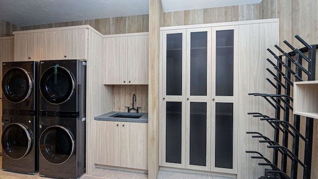 clothes washing area with stacked washing maching and dryer, wet bar, and a sink