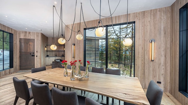 dining area with wooden walls and light wood-style floors