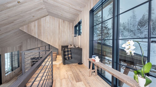 interior space with wood finished floors, lofted ceiling, wooden walls, wood ceiling, and an upstairs landing