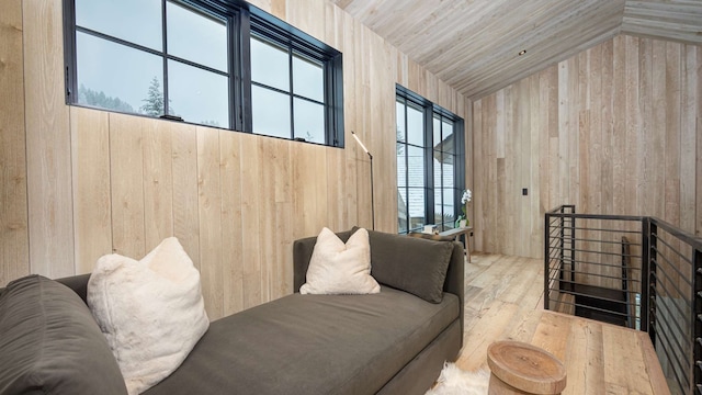 interior space with wooden walls, lofted ceiling, wood finished floors, and a healthy amount of sunlight