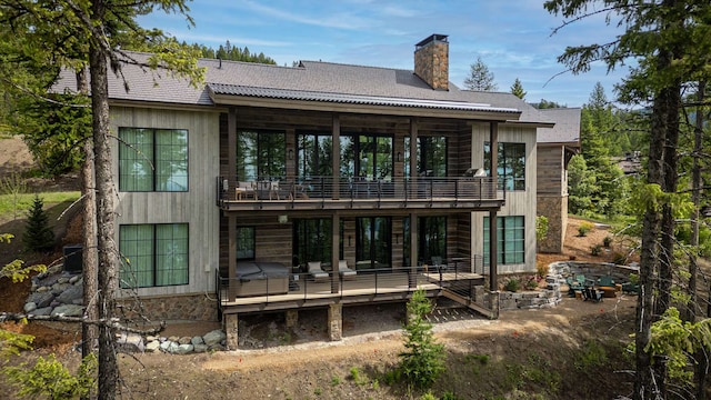 rear view of house featuring a chimney and a balcony