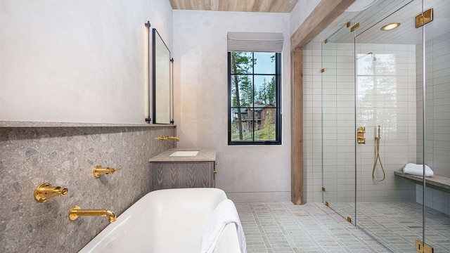 full bathroom featuring vanity, a freestanding bath, and a stall shower