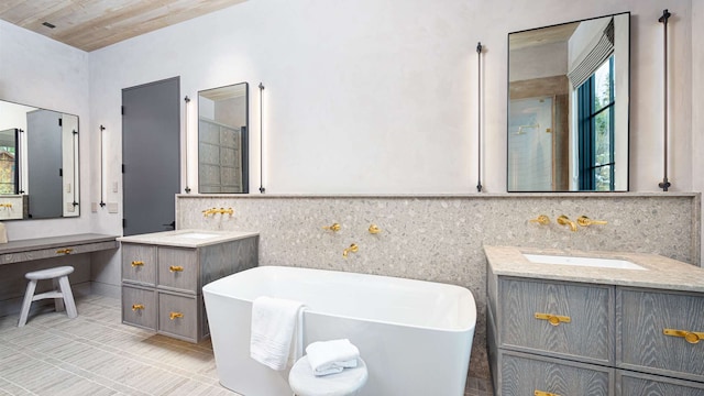 full bath with a sink, a freestanding tub, tile patterned floors, and two vanities