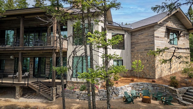 view of side of property with a fire pit, a wooden deck, and stone siding