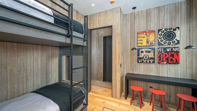 bedroom featuring a bar, wood walls, and wood finished floors