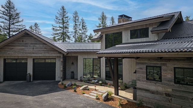 view of front of home featuring an attached garage, a chimney, and aphalt driveway