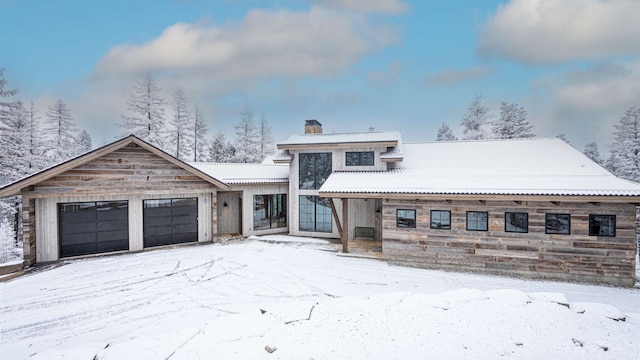 view of front of house with a chimney, metal roof, and a garage