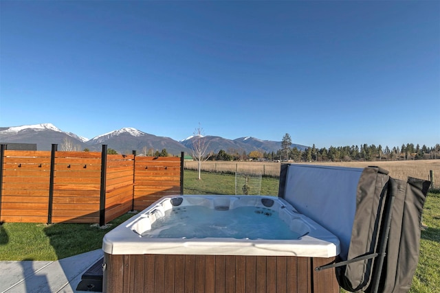 view of yard featuring fence, a mountain view, a hot tub, and a rural view