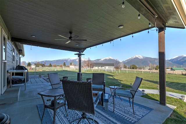 view of patio / terrace featuring outdoor dining area, a fenced backyard, ceiling fan, and a mountain view