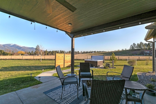 view of patio / terrace with fence, a shed, an outbuilding, a mountain view, and a rural view
