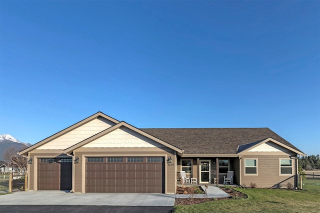 ranch-style house featuring a porch, a front yard, a mountain view, concrete driveway, and an attached garage