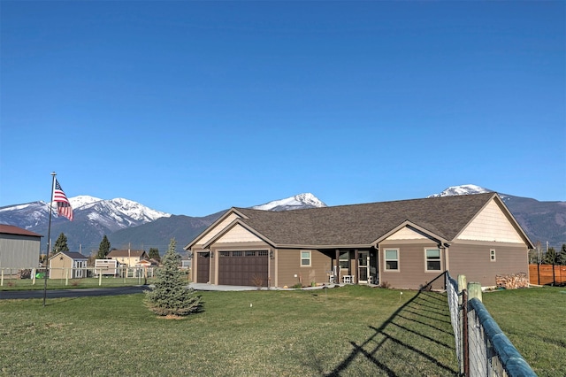 ranch-style house with a front lawn, fence, an attached garage, a mountain view, and driveway