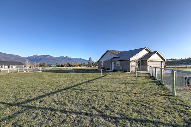 view of yard with a garage, fence, a rural view, concrete driveway, and a mountain view