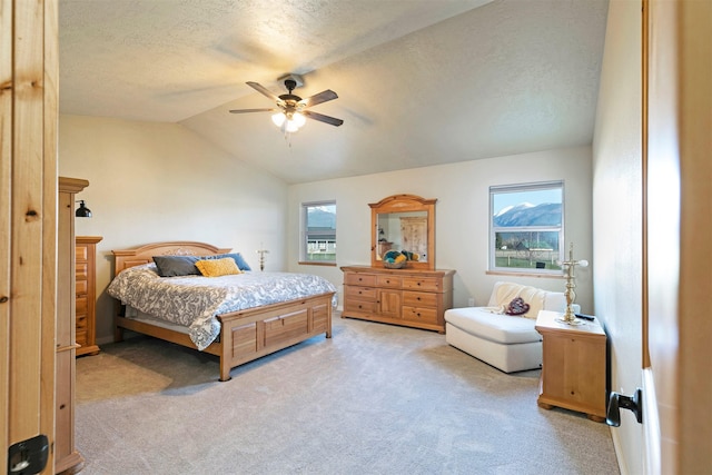 carpeted bedroom with a textured ceiling, ceiling fan, and vaulted ceiling