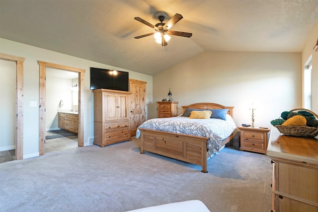 bedroom featuring baseboards, light colored carpet, connected bathroom, a ceiling fan, and vaulted ceiling