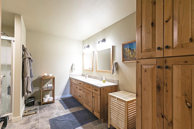bathroom featuring a sink, baseboards, a stall shower, and double vanity