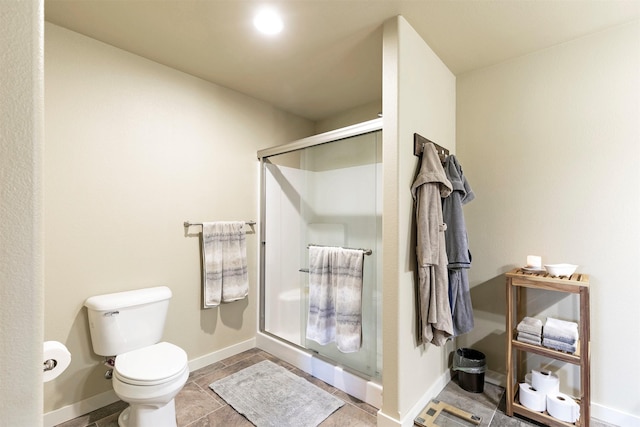 bathroom with toilet, baseboards, and a stall shower
