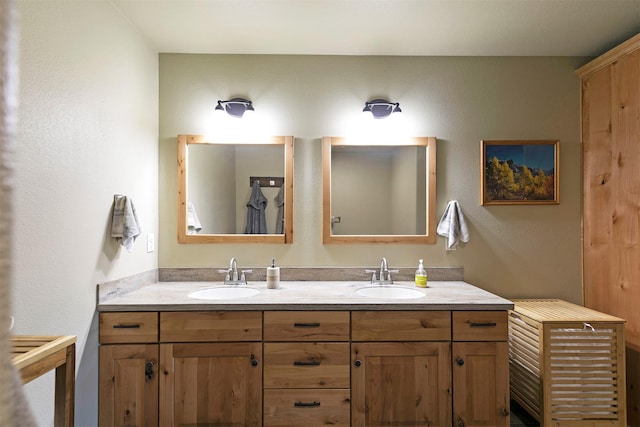 full bath with a sink, a textured wall, and double vanity