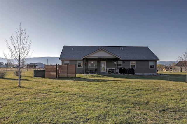 rear view of property with a yard, roof with shingles, fence, and a patio area