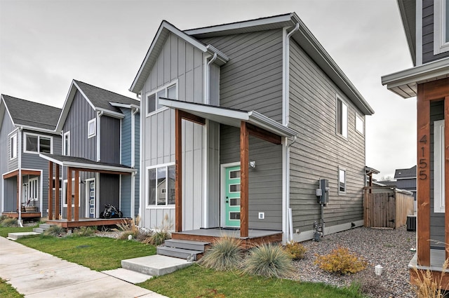 view of front of house featuring fence, board and batten siding, a porch, a gate, and central AC unit