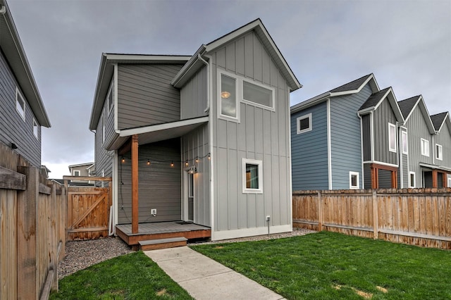 back of house with board and batten siding, a yard, and a fenced backyard
