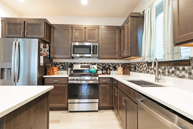 kitchen featuring a sink, appliances with stainless steel finishes, light countertops, and dark brown cabinets