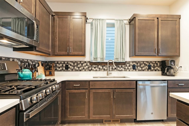 kitchen with visible vents, dark brown cabinets, a sink, light countertops, and stainless steel appliances
