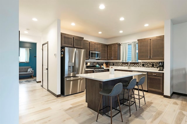 kitchen featuring light wood-style floors, a breakfast bar, dark brown cabinetry, and stainless steel appliances