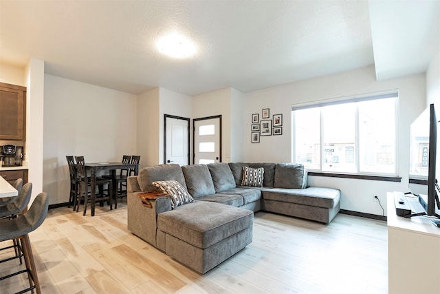living area with light wood-type flooring and baseboards