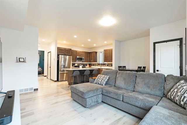 living room featuring recessed lighting, visible vents, and light wood finished floors