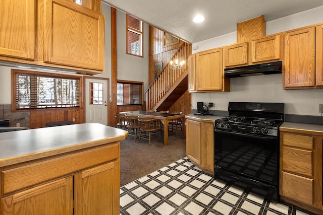 kitchen featuring light colored carpet, black range with gas stovetop, light countertops, light floors, and under cabinet range hood