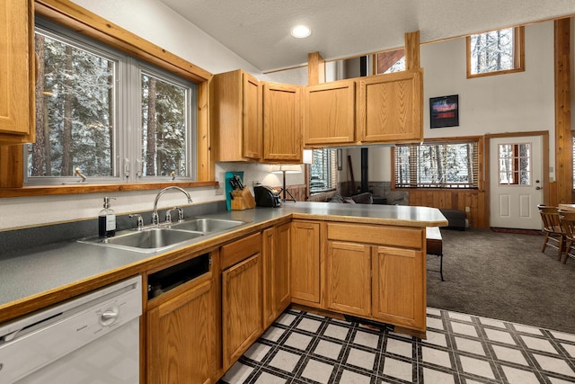 kitchen featuring white dishwasher, a sink, a peninsula, open floor plan, and light floors