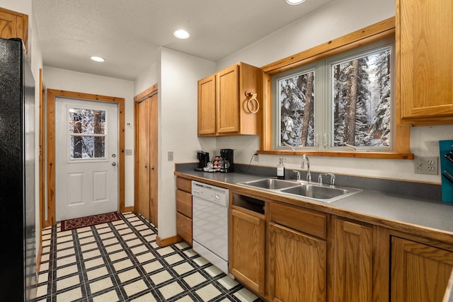 kitchen featuring white dishwasher, a sink, freestanding refrigerator, light floors, and recessed lighting