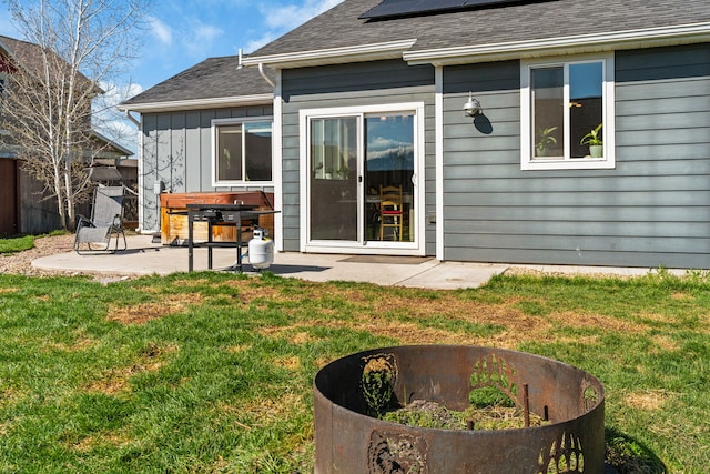 back of property featuring board and batten siding, solar panels, a lawn, a patio, and a shingled roof
