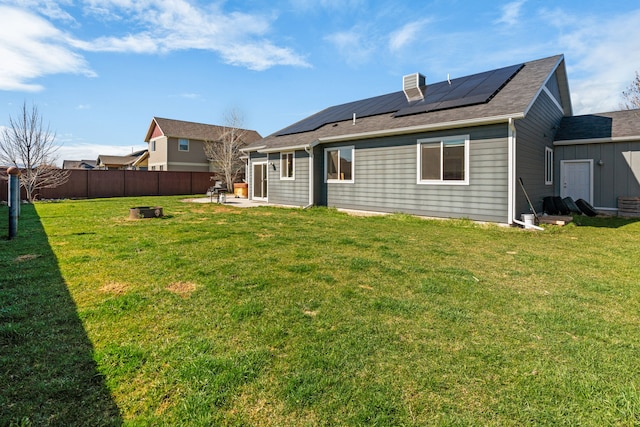 back of house featuring a lawn, solar panels, a fire pit, and a patio