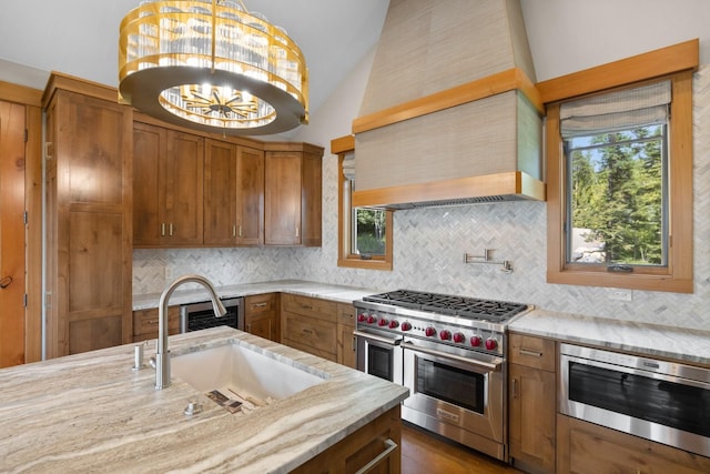 kitchen with range with two ovens, built in microwave, brown cabinets, a sink, and lofted ceiling