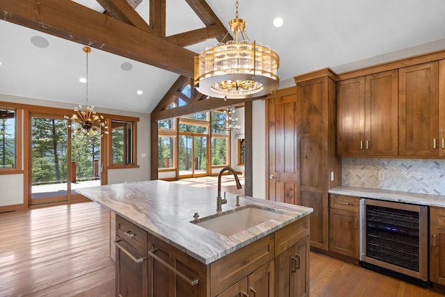 kitchen with a notable chandelier, a sink, brown cabinetry, light wood-type flooring, and wine cooler