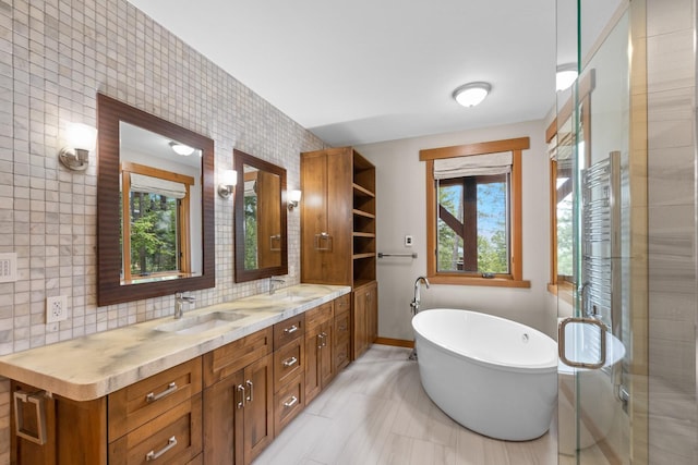 bathroom featuring a sink, a freestanding bath, double vanity, and a wealth of natural light