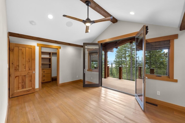 interior space with baseboards, vaulted ceiling with beams, and light wood-style floors