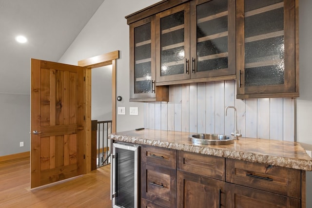 bar with light wood-style floors, a sink, lofted ceiling, and wine cooler
