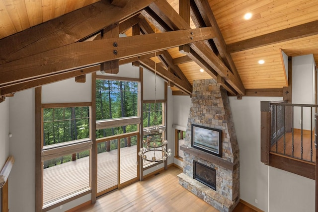 unfurnished living room with lofted ceiling with beams, wood finished floors, and a fireplace