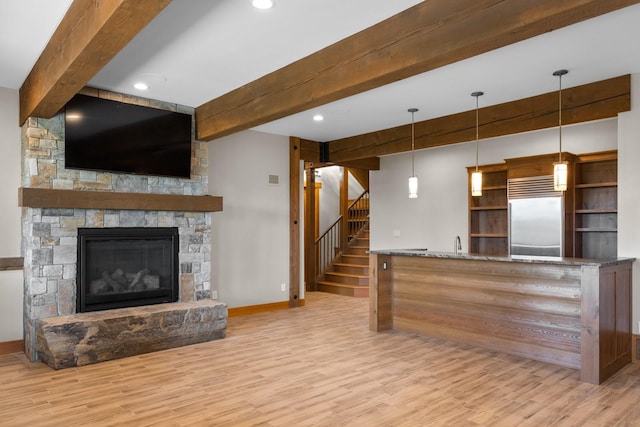 unfurnished living room with baseboards, stairs, beam ceiling, and wood finished floors