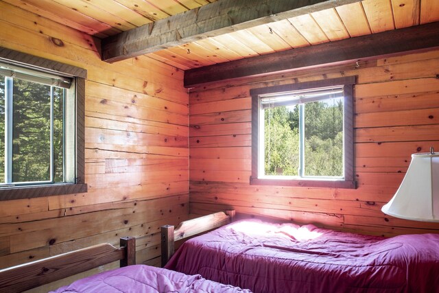bedroom featuring wooden walls, beamed ceiling, and wooden ceiling