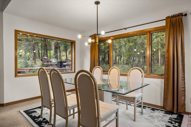 dining space featuring carpet flooring, baseboards, an inviting chandelier, and a healthy amount of sunlight