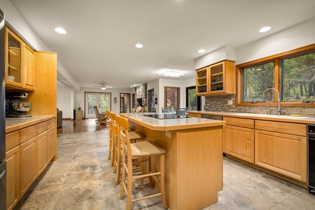 kitchen featuring a breakfast bar area, stone finish flooring, a center island, a sink, and recessed lighting