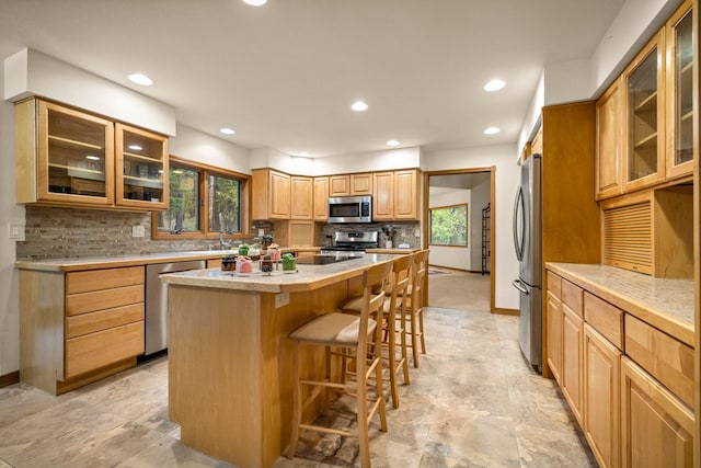 kitchen featuring backsplash, a kitchen breakfast bar, appliances with stainless steel finishes, and a wealth of natural light